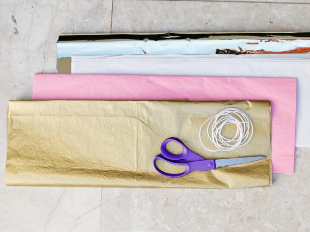 To start your tissue paper tassels, fold a piece of tissue paper in half and in half the other way.