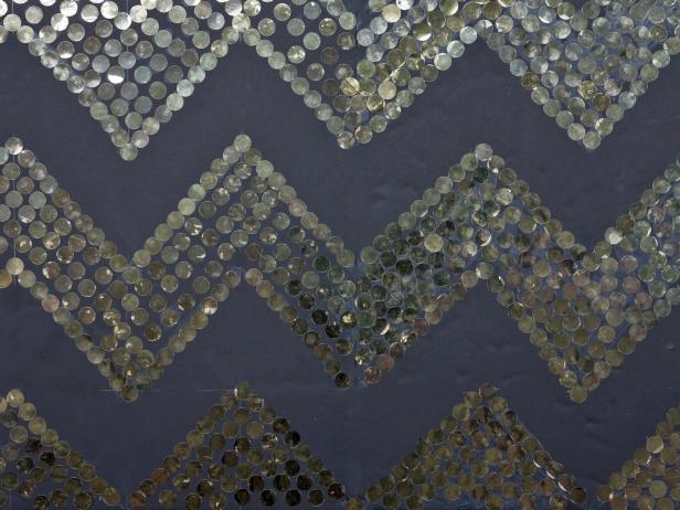 This is where you get to show off your creative skills. A printed fabric backdrop is most common, but why limit yourself to store-bought options? Make one that adds life to the photos. Create a chevron-inspired backdrop with black foam board, a glue stick and jumbo gold sequins. Draw the chevron stripes using a ruler, then fill in rows of sequins.