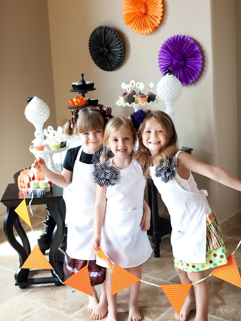 Three Little Girls Holding Orange Banner at Halloween Party