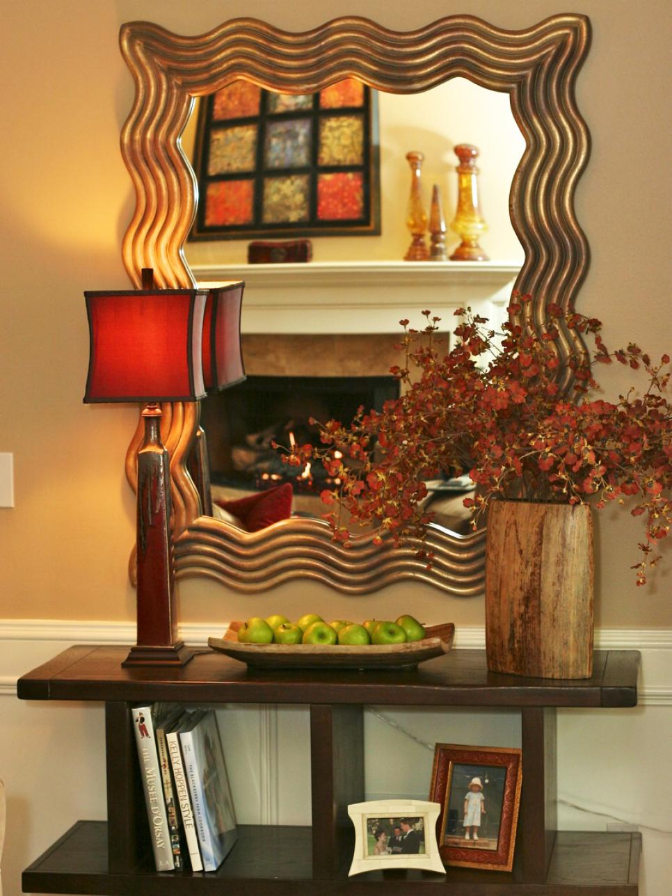 Wavy-Framed Mirror Above Brown Symmetric Bookshelf Living Space With Bookshelf Storage and Brass-Framed Mirror