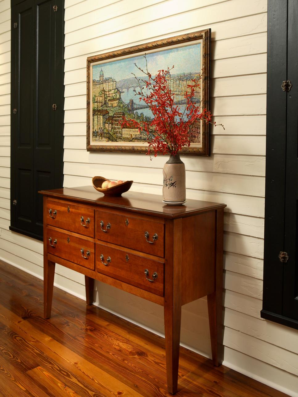 Entry Space With White Wood Siding, Black Shutters and Wood Credenza