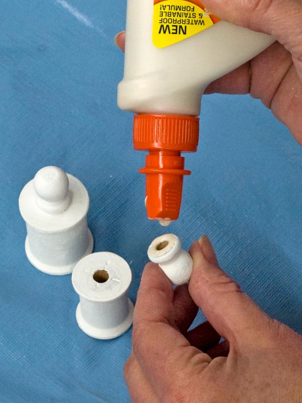 To make each ring stand, use wood glue to attach a wood ball finial to the top of each spool (Image 1).