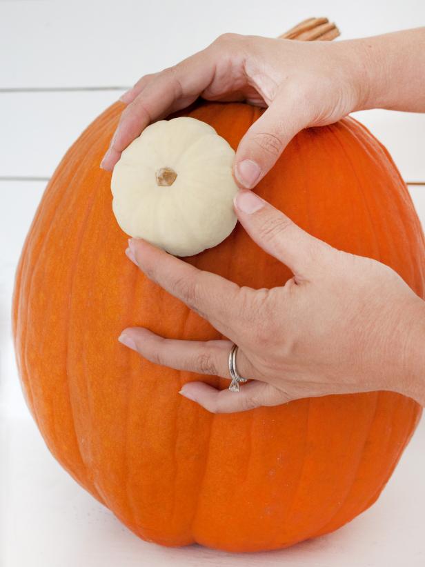 Push two toothpicks into the front of the large pumpkin where the eyes will be positioned. Gently push the bottom halves of the small pumpkins onto the toothpicks.