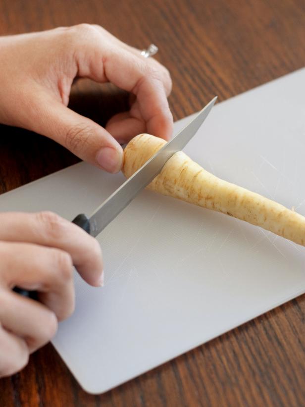 Use a sharp knife to cut off the top of each carrot and parsnip.