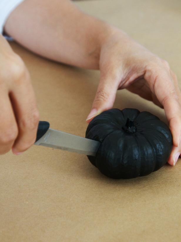 Person cutting slot for wings in pumpkin