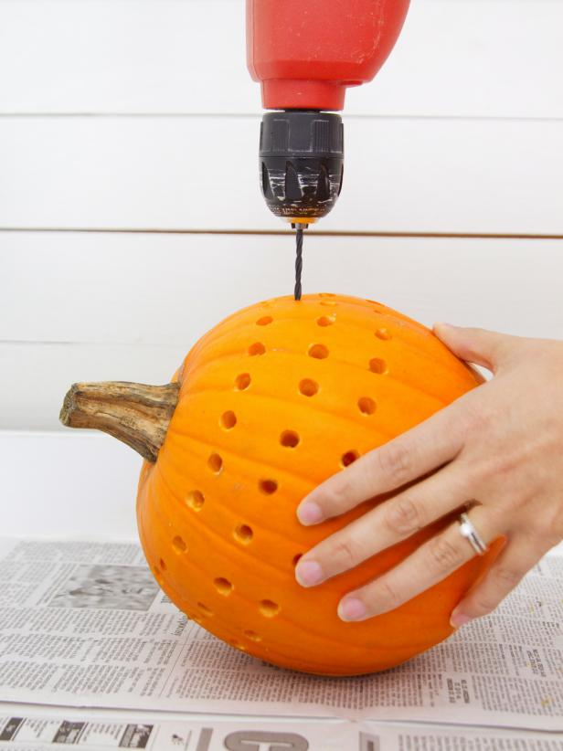 Replace the large drill bit with a much smaller one and proceed to drill smaller holes in between and above each of the large ones, all the way around the pumpkin.