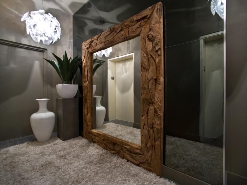Driftwood-Framed Mirror Reflecting Elevator Doors in Neutral Foyer