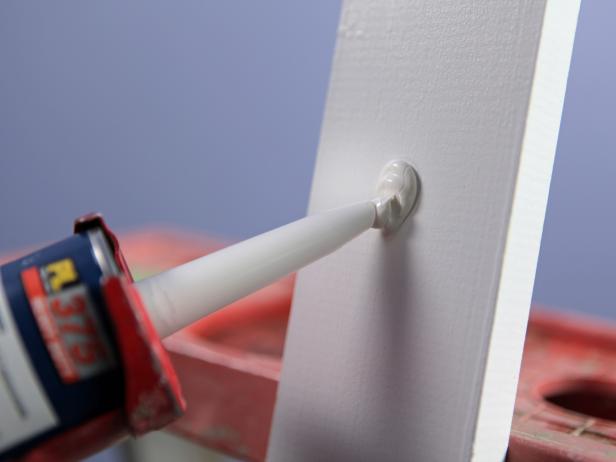 With each of the two center pieces of vertical trim in their proper position, add a bead of liquid bonding adhesive to the back and press into place in order to hold them while nailing.