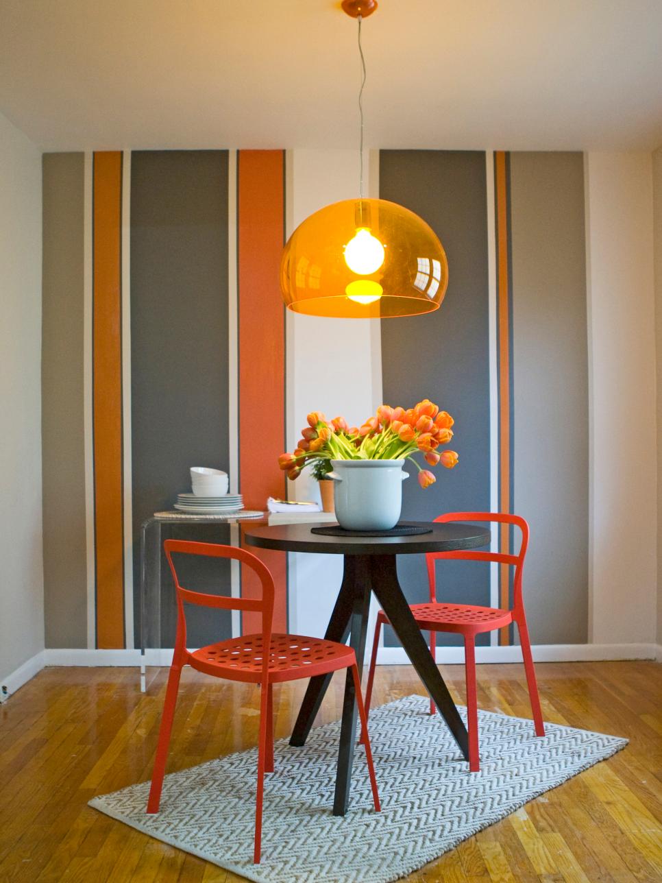 Dining Room With Striped Accent Wall & Shades of Orange
