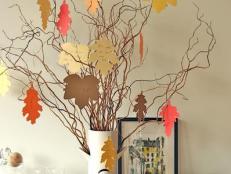 Multicolored Paper Leaves Hang on Spindly Branches in White Vase