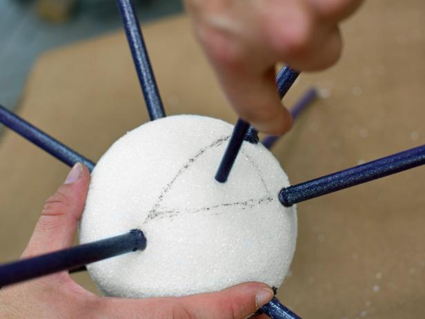 This triangular shape will be used as a guide for the placement of each 1/4" dowel. Next, Insert a 1/4" dowel directly into the marked triangle's center. Once a hole has been created, remove dowel, and add glue to its tip then reinsert it. Repeat this step until all 1/4" dowels are in place. Note: Don't forget to leave a dowel-free area on the bottom of the sphere so the topper will better sit atop the tree.