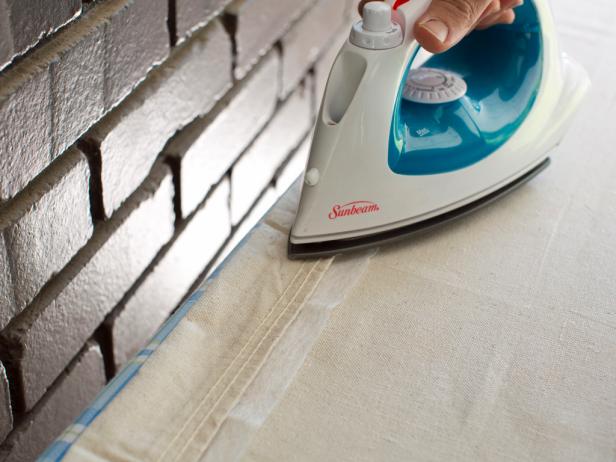 Create a rod pocket by folding the drop cloth's top down approximately 1/2", then use iron-on adhesive tape and iron to fuse the two portions of the drop cloth together