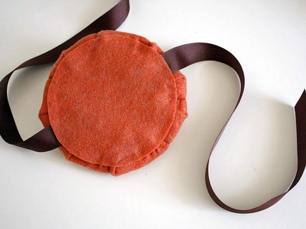 Cut about 1 1/2 yards of ribbon and lay it across the middle. Then seal fabric in place by gluing the smaller felt circle on top.