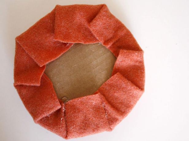 To create the pumpkin shape, stack a circle of felt plus two layers of quilt batting and the cardboard circle together. Glue in place.