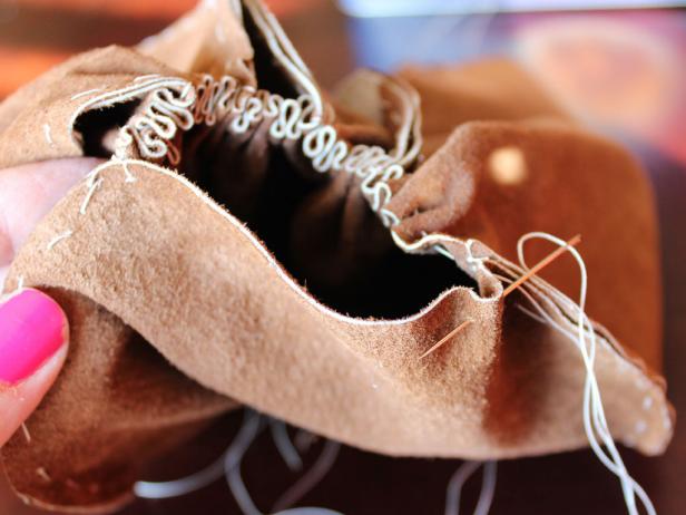 Stitch all the panels together until you end up with a tube. Next, stitch and gather the bottom of the tube. Gather it together as tightly as possible. The pumpkin is starting to take shape. Then start gathering the seams on the panels. Pull on the thread until the sides of the pumpkin are gathered to your liking. Try to keep all the gathered seams even.