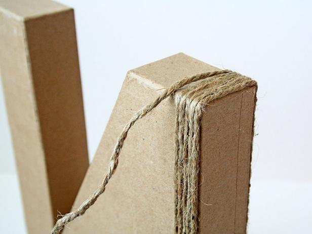 After wrapping one section of the N vertically, begin wrapping in the opposite direction with the other roll of jute. Secure the jute with glue every 5 to 6 rows.