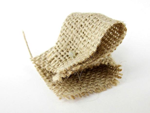 Take the left-hand corner (pinch one layer of fabric on the very tip) and take it to the back. Line up the corners. All four corners should be lined up at the bottom.