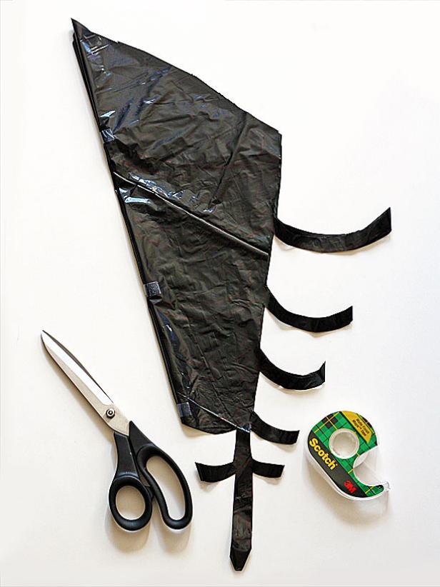 Begin by laying a trash bag out flat. Trim off the sides and bottom so you're left with two big rectangles of plastic. Cut each piece into an approximate square (eyeballing it is fine). Fold one of the squares in half diagonally to form a triangle. Fold that triangle in half two more times.