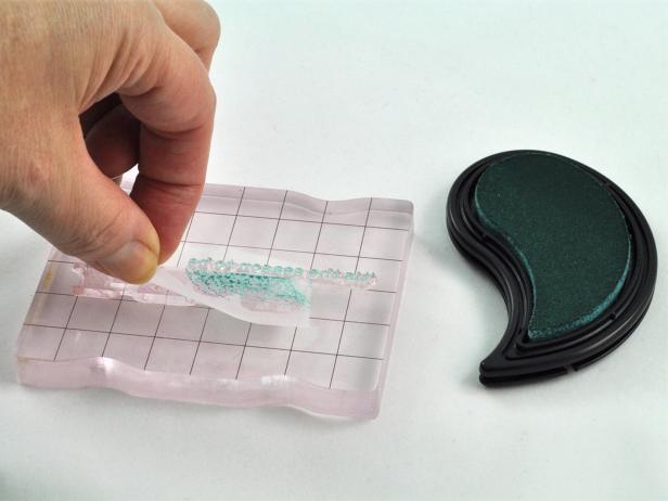 In step 2,create a multicolored sentiment. Start with a clean stamp and mask off parts of the sentiment that do not need to be inked in the first color with regular tape. Ink, then remove tape mask before stamping first color. Clean stamp, then repeat the masking step before inking with second and third colors. Tip: To get a two-toned sentiment, ink sentiment first in the lighter of the two colors, then ink only one edge in the darker color.