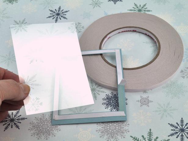 Cut window/acetate sheet slightly smaller than outside dimensions of frame. Line frame with high-tack, double-sided tape and peel release liner from tape for snow shaker holiday card.
