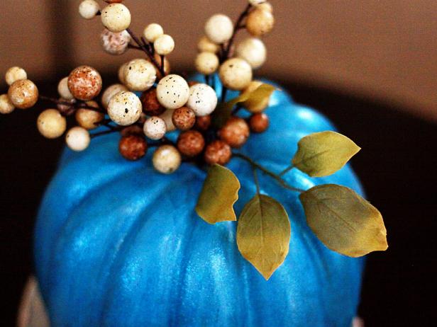 Cut apart decorative &quot;holiday picks&quot; and glue them to the top of the pumpkins.