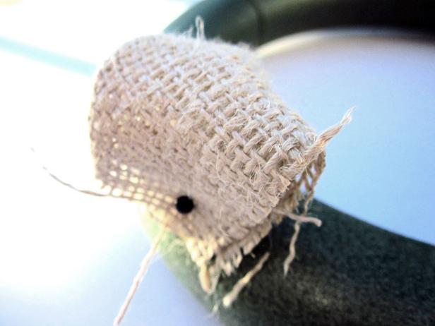 All four corners of your burlap square should be lined up at the bottom. Pin the "bubbles" to the wreath. Pin one bubble on and then place the next one close to it so that it hides the pin on the one that you just added.