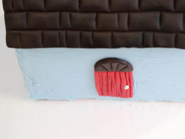 Place the chocolate fondant piece on top of the door adhering with royal icing.