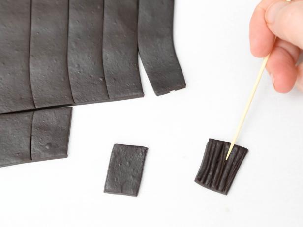 Serrate each fondant piece with a toothpick or the back of a knife to begin making the roof.