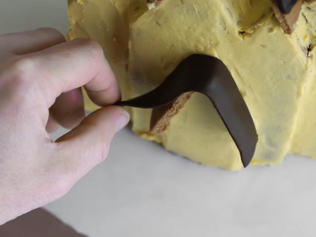 In step 19 of this project, cut a 4 3/4-inch long x 1-inch wide piece of fondant that has been rolled to 1/4-inch thickness. Dab porch eaves with a little royal icing and drape fondant over. Trim away excess fondant with a sharp knife.