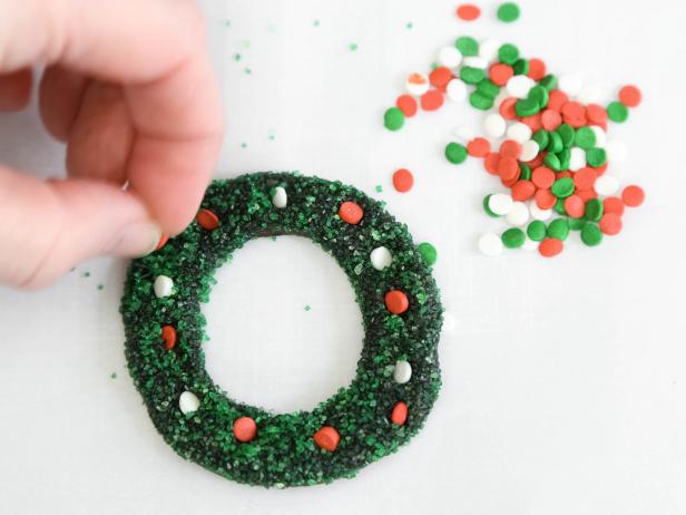 Press confetti sprinkles into a gingerbread house wreath for decoration, if desired. Let set until partially dry. Adhere wreath to the left of the door using royal icing.