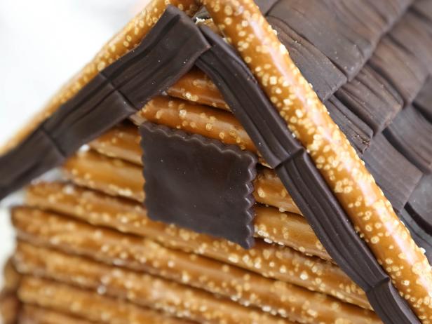 Cut a 2x2-inch square of chocolate fondant and adhere it just below the peak of the roof using royal icing.