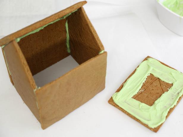 Coat the under edges of the gingerbread roof pieces with the melted candy.