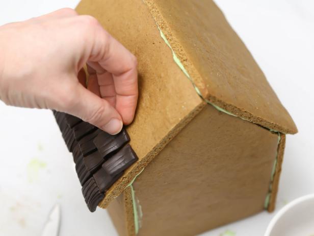 Attach the chocolate fondant pieces to the roof beginning at the bottom edge and working upward.