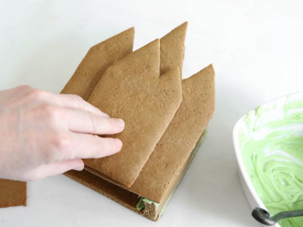 Use warm candy melts to construct and attach the gingerbread pieces to form the Victorian home and porch.