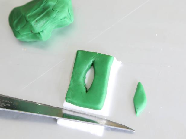 In step 24 of this project, place the rectangle on a scrap piece of white fondant rolled to 1/4-inch thickness. Cut to size and roll flat with a rolling pin.