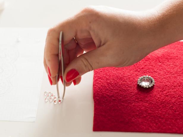 Pick up crystals with tweezers then apply glue to the backs before attaching it to the felt.
