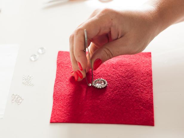 Start applying the medium crystals around your design to create another circle. Tip: Pick up a crystal with tweezers then apply glue to the back before attaching it to the felt