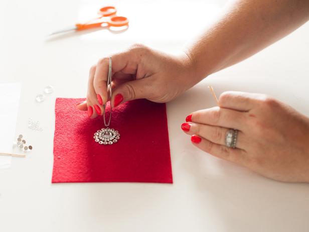 Start applying the medium crystals around your design to create another circle. Tip: Pick up a crystal with tweezers then apply glue to the back before attaching it to the felt.