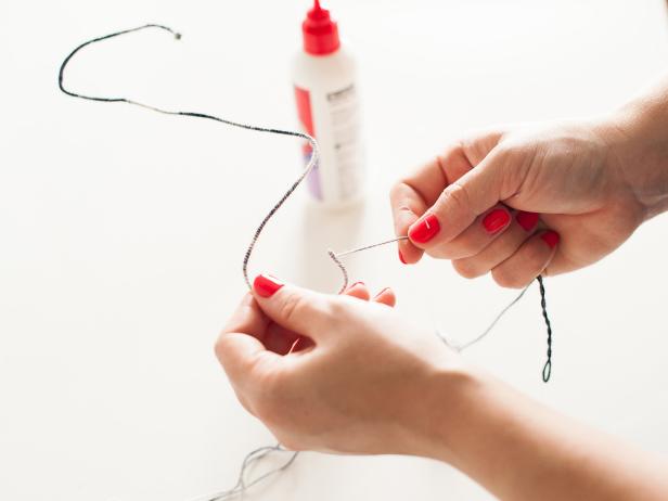 Keeping the yarn taught, add a small line of glue then cover it with the wrapped yarn until the entire initial is covered. At the end of the wire, wrap the yarn back over its self a few times.