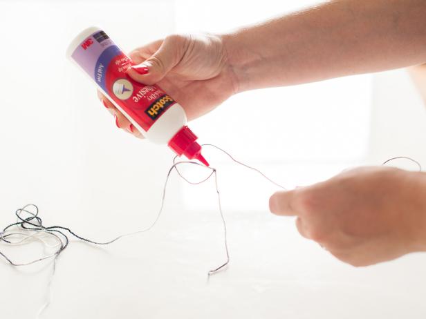 Cut off any excess wire and unbend the swirls on the ends slightly to make wrapping the letter with yarn easier. Knot the yarn around one end of the initial and top the knot with a dot of glue to secure it.