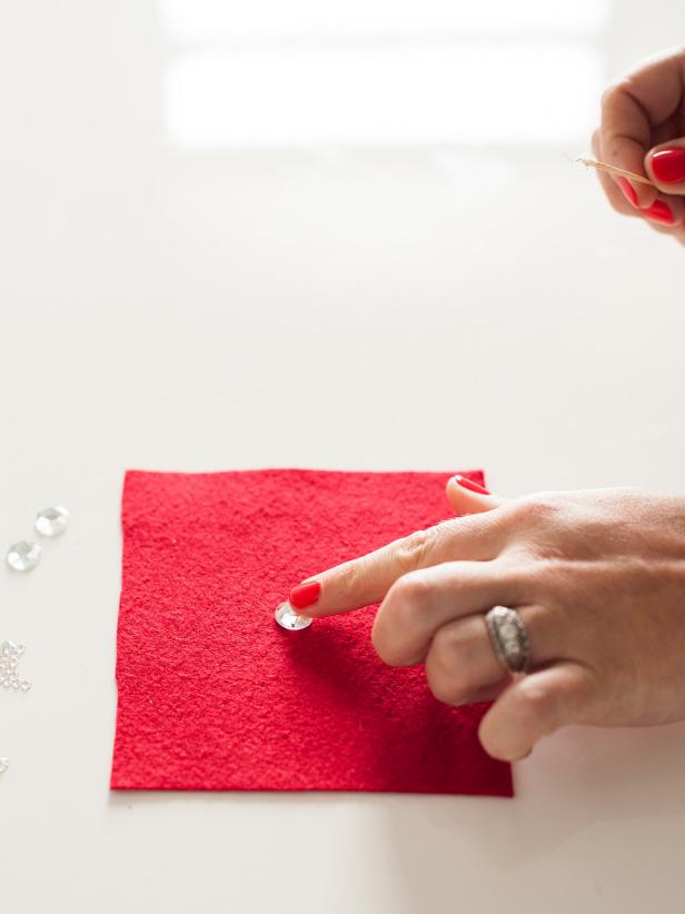 Use a toothpick to apply glue to the back of the center, large rhinestone then glue the crystal to the center of the felt.