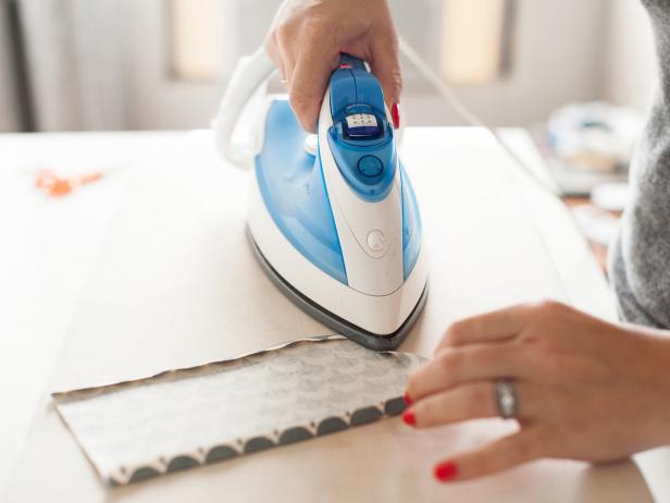 With the right-side-down, iron a 1/4" hem on each side of the lining fabrics and the lining flap piece.