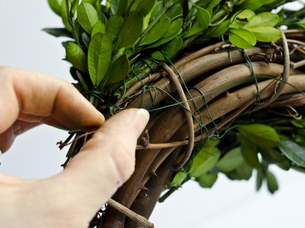 Repeat with the next row, allowing bunches to overlap by a couple of inches. Repeat this process until the entire front side of the wreath is covered. Tip: The final bunches can be wedged into the grapevine sticks instead of secured with wire.