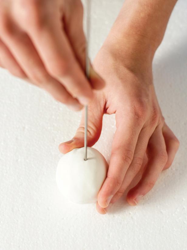 Begin stringing the balls onto fishing line by inserting the upholstery needle with fishing line attached into the center of one the foam balls.