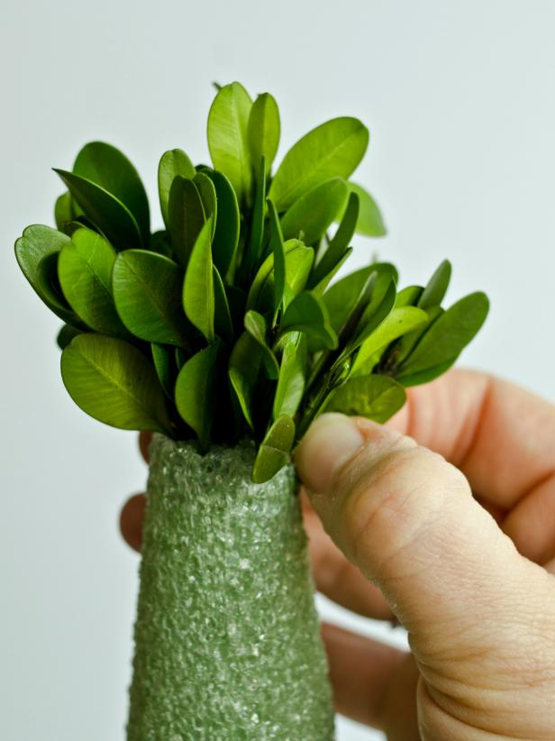 For a cone-shaped topiary, create 4-5 bunches of boxwood sprigs by gathering 3-4 individual sprigs and bundling them together with a length of florist wire. Tuck bunches into top of form