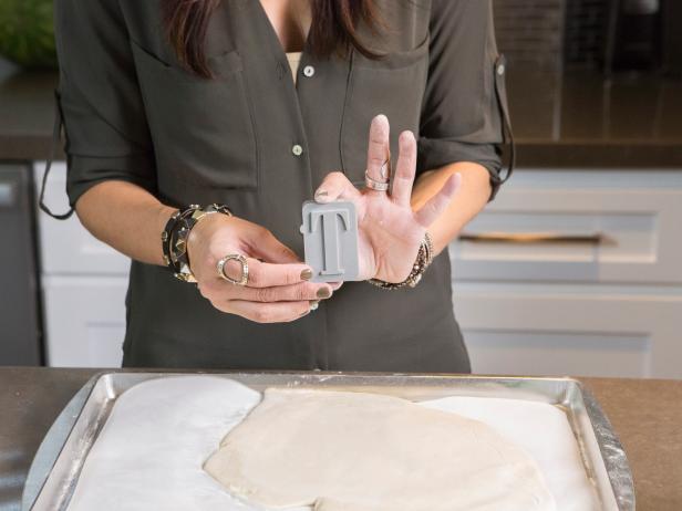 Designer Laurie March, who has a plan to transform the living room and foyer of TV personality Kendra Wilkinson and husband Hank Basketts (retired NFL player) into a glittering, disco-inspired Holiday wonderland, shows the secrets of DIY salt-dough cookie ornaments. Using an alphabet letter mold, she presses it into soft cookie dough to imprint the letter's shape in the dough, before flipping the mold and pressing it again to use its edges to cut arond the imprinted letter, which is then oven baked until it hardens, and finally spray painted, as seen on HGTV's Celebrity Holiday Homes.