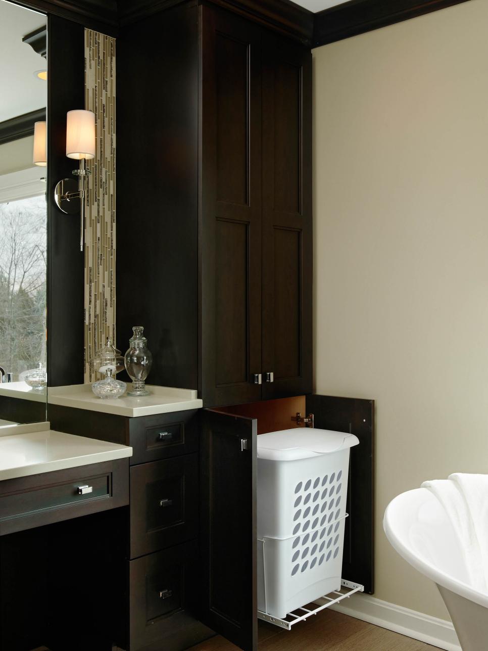 Dark Cabinetry With Hamper Pullout in Neutral Bathroom