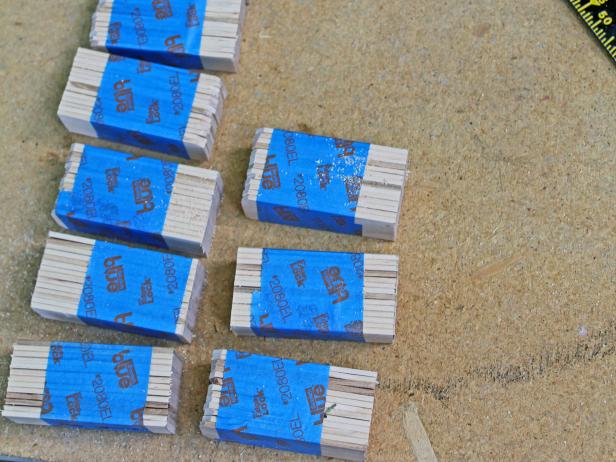 For final two groups of sticks, measure and mark the first length, then measure the same distance towards the center of the sticks. Make two cuts with a hand saw. Lightly sand the ends of each bunch, then unwrap tape. Now you're ready to start the assembly!