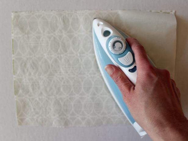 Cut a piece of fabric and fusible web that are approximately the same size as your felt sheet. Flip fabric over, place fusible web glue-side-down (has a slightly shiny, rough texture) and press for 5 to 8 seconds with a hot, dry iron.