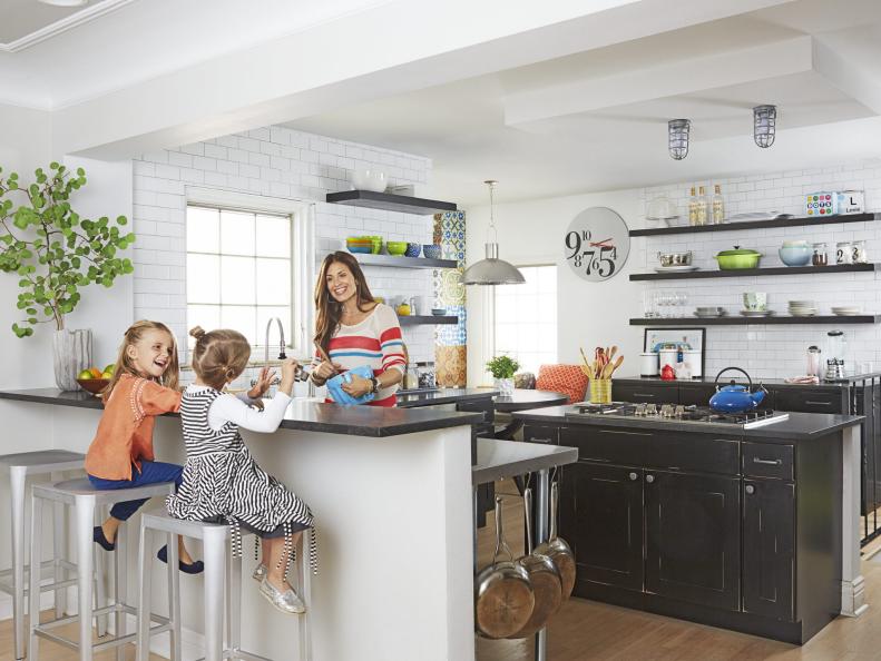 Mother and children in a large, black and white, open kitchen.